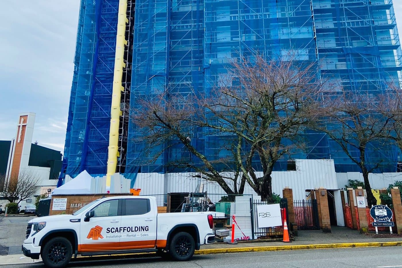 A&K Scaffolding truck parked at a high-rise wrapped in scaffold and debris netting, Maple Ridge