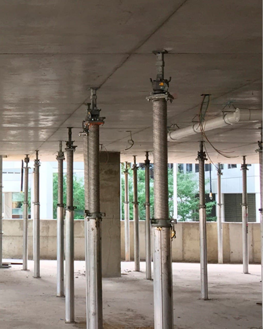 Rows of adjustable steel props holding a concrete slab from the floor below