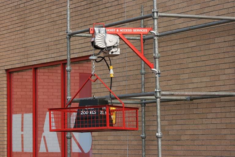 Material hoist mounted on scaffold