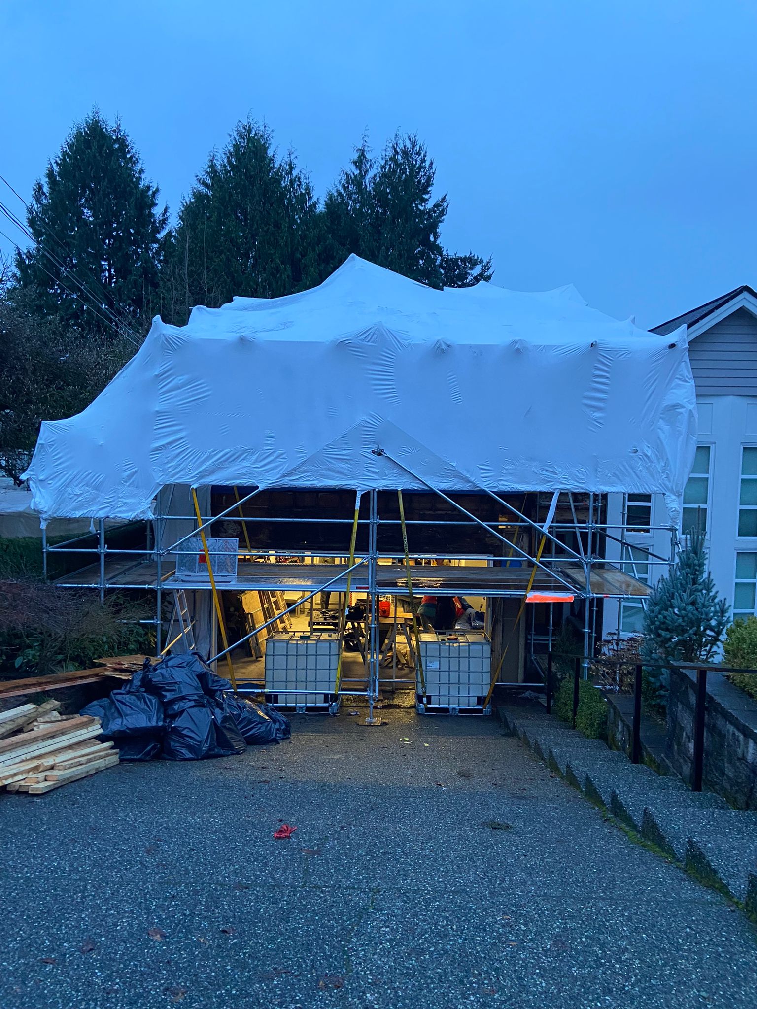 Residential building fully enclosed in white shrink wrap for weather protection while work continues inside
